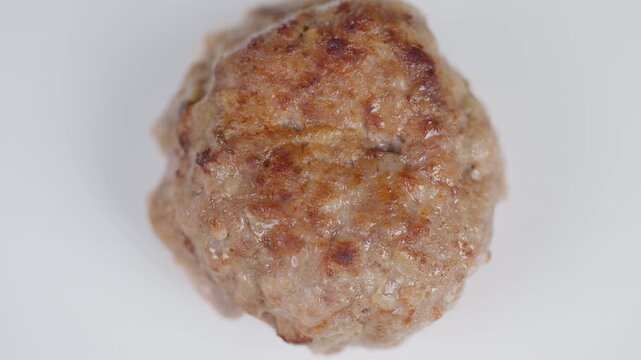 Closeup of goldenbrown homemade meat patty. Upclose view of crispy crust and tender interior. Appetizing homemade meat cutlet with juicy filling on simple white dish