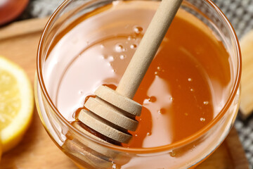 Jar of sweet honey with dipper on table, closeup