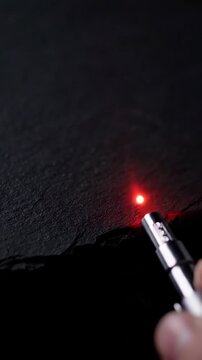 Laser pointer aiming a red beam on a dark surface