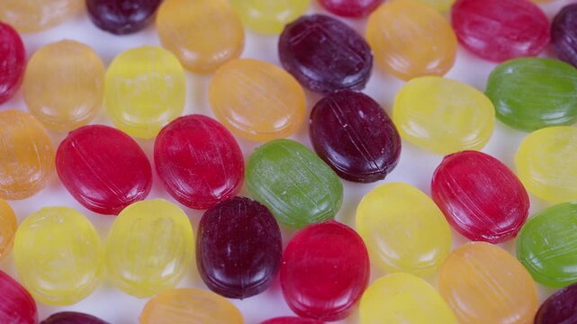 Colorful candy display. Colorful sugary confections with vibrant hues in focus shot. Multicolored hard candies with glossy surfaces scattered against clean white backdrop