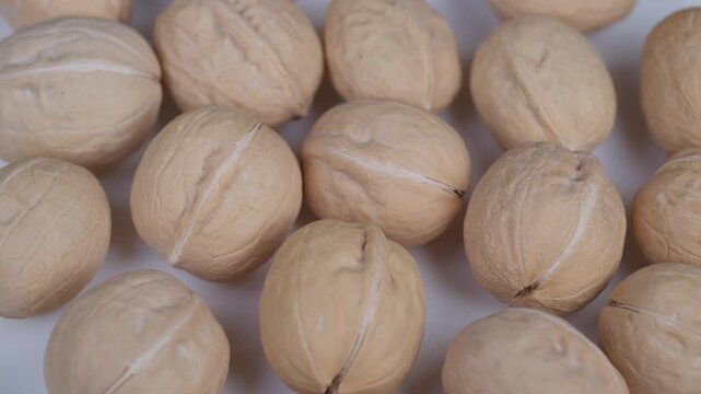 Highresolution macro photograph of whole walnut shells on white surface. Closeup shot showcasing intricate textures and natural characteristics of walnut shells