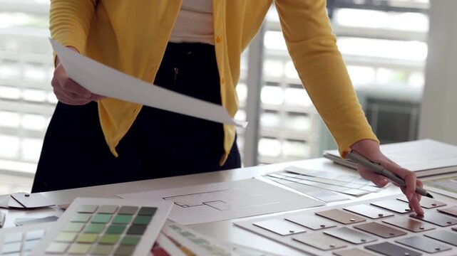 Professional designer busy selecting color palettes material samples reviewing blueprints office environment creative process architecture interior design studio planning projects