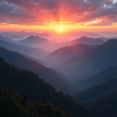 Naklejka premium Sun rises over misty mountain range valleys. Orange light breaks through clouds creating rays. Silhouettes of hills show layered landscape. Serene nature view.