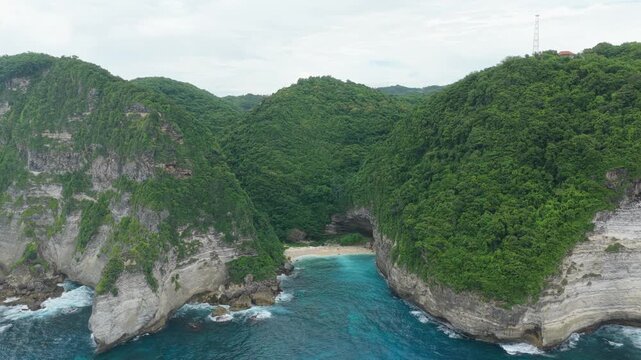 Drone flying towards secluded sunfish beach in nusa penida bali