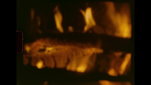 Flames and logs burn brightly in a fireplace providing warmth and light captured on analog super 8 film