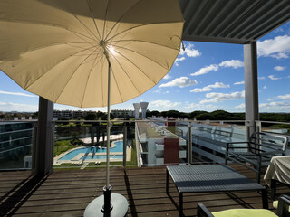 Fototapeta premium An inviting balcony space with comfortable seating, decorative plants, a small table, and a view overlooking modern residential buildings on a cloudy day.