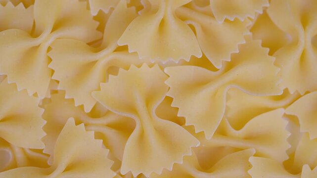 Pasta pattern closeup. Close view of bowshaped pasta with warm tones. Intimate perspective showcasing dry bowtie pasta with intricate edges and cozy kitchen ambiance