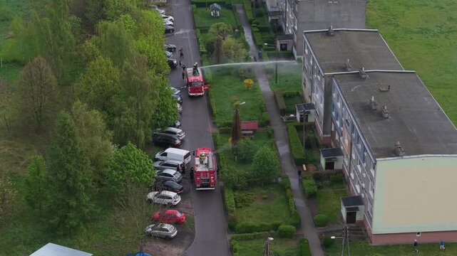 Volunteer firefighters from a rural Polish village celebrating Wet Monday (Śmigus-Dyngus), joyfully splashing water and playing with local residents in a festive spring tradition