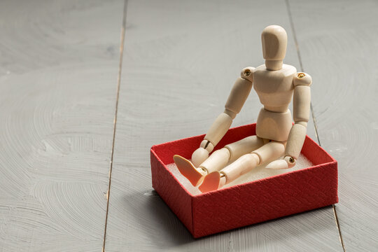Wooden doll toy in a red gift box on white background