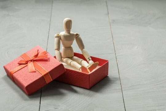 Traditional wooden peg doll in red gift box on white background