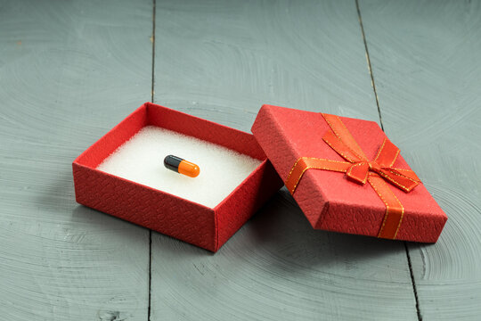 Single medical pill in an open red gift box rare expensive medication