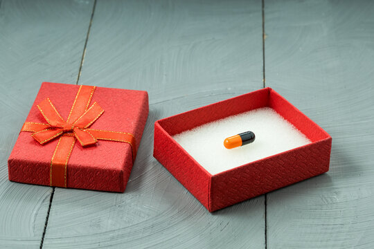 Red gift box with one precious pill inside rare medicine for serious illness