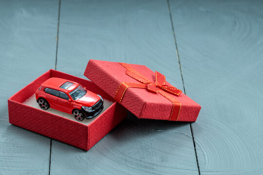 Red toy car in matching red gift box, cohesive luxury present concept