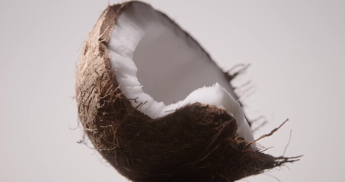 Closeup of a Hairy Brown Half of a Cracked Coconut with White Flesh, Isolated on a White Background. Studio shot, local light, 60 fps.