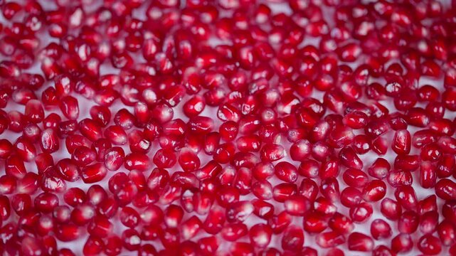 Lush crimson seeds shimmer beautifully. Juicy red arils scattered vividly on surface. Tiny gleaming crimson arils covering surface showcase freshness and culinary elegance