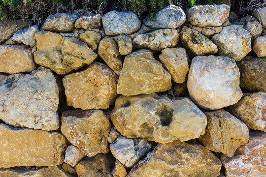 Dry Stone Wall Made of Rough Limestone Rocks With Mediterranean Shrubbery on Top