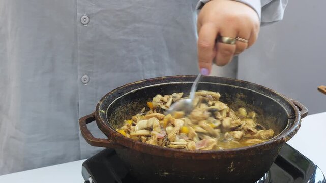 Chicken, onions, and champignons in teriyaki sauce are fried in a deep cast-iron skillet
