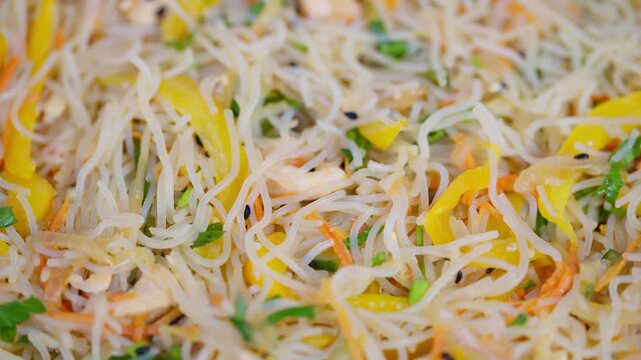 Fresh vegetables with delicate noodles. Colorful rice noodles with crispy vegetables and light dressing. Appetizing closeup of vegetableinfused rice vermicelli with sesame sauce
