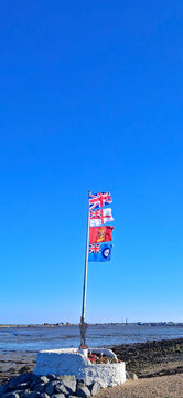 Armed forces memorial with military flags flying against blue sky.