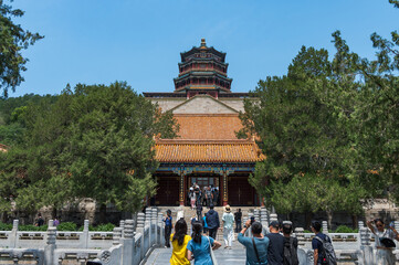 Obraz premium A bustling scene of tourists crossing a stone bridge leading towards the majestic Tower of Buddhist Incense at the Summer Palace in Beijing, China - 27 May 2025