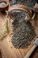 Lentilles vertes crues en bocal sur planche rustique en bois