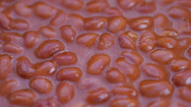 Glossy red beans in sauce, Closeup of shiny red beans in warm home style setting, Detailed shot of lacquered red beans with simmering bubbles and rich flavor sheen