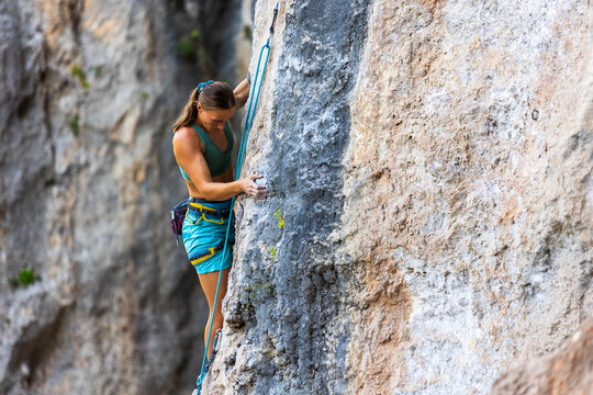 Extreme sports and active lifestyle. Young female rock climber. A female rock climber conquers a very difficult route, performing complex moves.