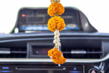 Traditional Thai flower garland swinging from a rearview mirror in a moving taxi for luck and...