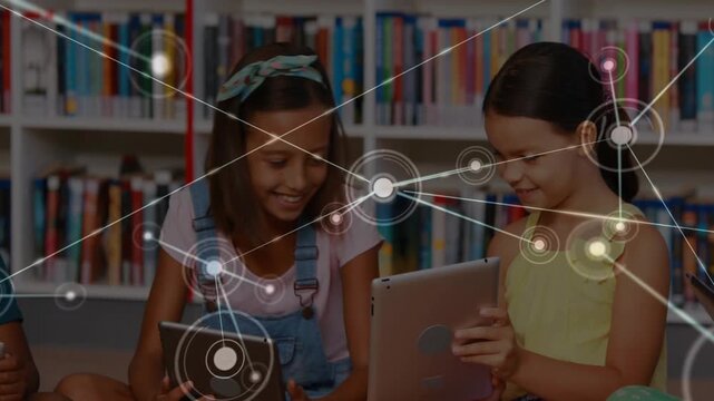 Two girls tapping tablets and sharing screens in classroom, animated network growing to link ideas