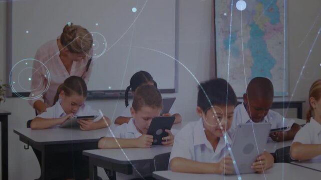Teacher in class leaning over tablets stepping back adding glow and screens lit as students working