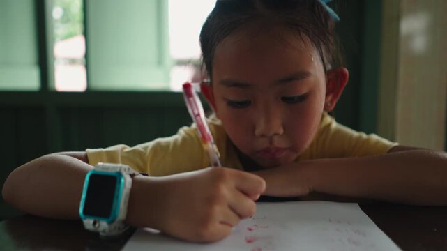 Asian girl doing schoolwork writing on a wooden table calmly