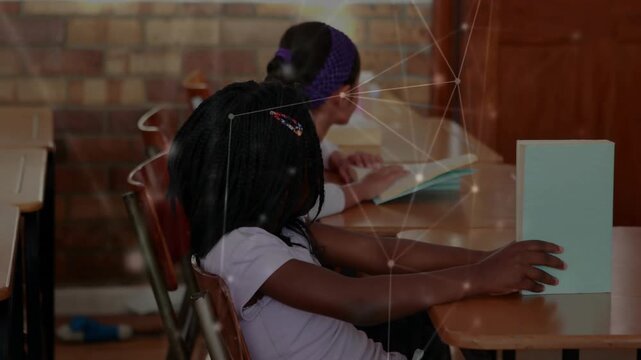 Front student repositioning blue book to desk edge, school network tracking book while peer reads