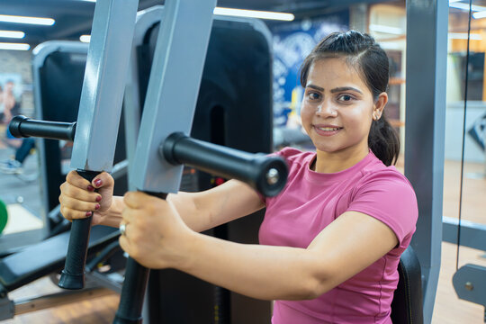 Indian Woman Performing Butterfly Exercise on Pec Deck Machine During Chest Workout in Modern Gym