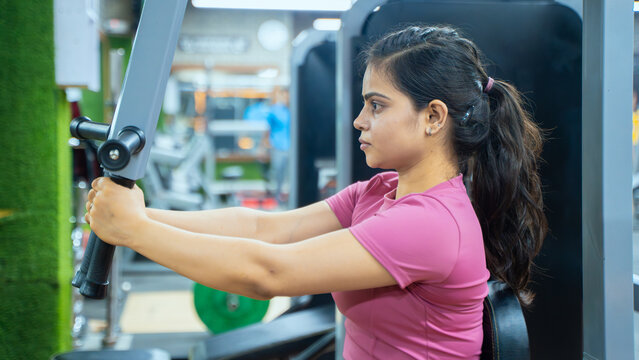 Indian Woman Performing Butterfly Exercise on Pec Deck Machine During Chest Workout in Modern Gym