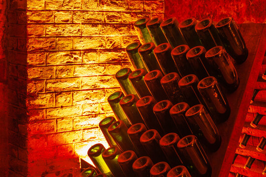 Champagne bottles on wooden racks in the traditional process of riddling (remuage) in sparkling wine production in underground chalk cellars of Reims, Champagne province of France