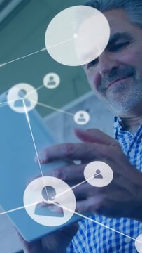 Mature man lowering tablet and tapping, activating network icons growing across frame for business