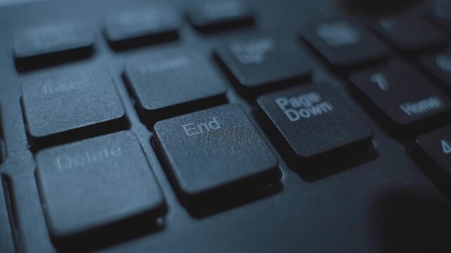 Extreme close up on computer keyboard End button being pressed by finger. Person clicking on key to end program command or terminate task or software. Hacker or programmer code finishing mission