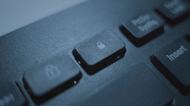 Close up on finger pressing padlock button or key on computer keyboard. Dark room at night man clicking on lock icon key on keyboard. Unlocking or locking access to file document or secret data folder