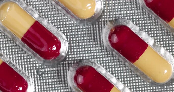 Zenithal shot of spinning red pharmaceutical blister packs for a comprehensive view of modern medical treatments and health care.