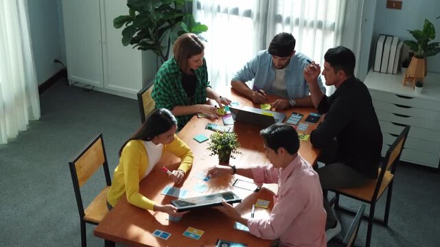 Top view of business team writing sticky notes while manager working on tablet and looking at analysis data. Group of diverse people sharing or exchanging marketing plan. Creative work. Convocation.