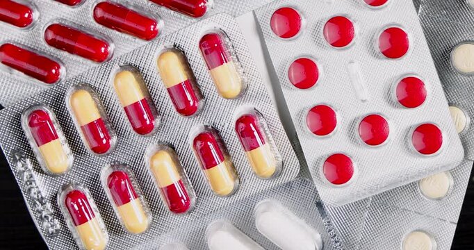 Zenithal perspective of spinning pharmaceutical blisters with assorted colored pills for a comprehensive view of modern medicines.