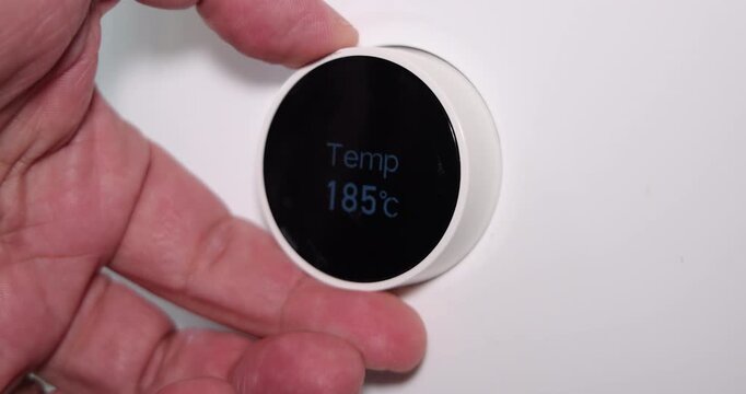 Detailed shot of a hand selecting the menu on a white air fryer control panel using the mechanical dial for cooking crispy food.