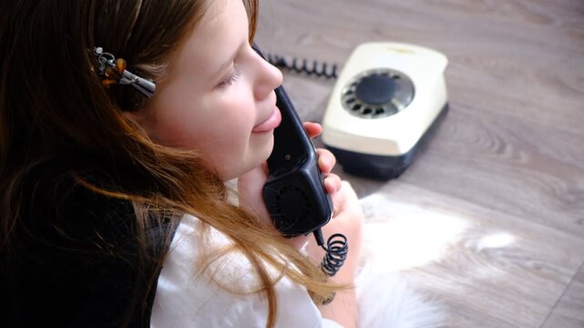 Teenager girl with a vintage rotary phone, ready to make a call. Pretty teenager girl talking to someone on the phone. Living room, cozy home