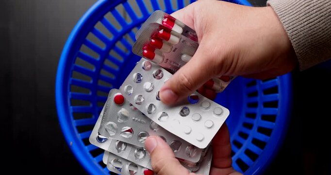 Person throwing used pill blisters into a blue trash bin representing medical malpractice and pharmaceutical medication errors.