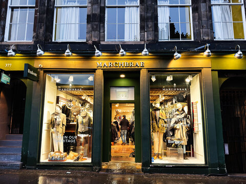 Marchbrae clothing shop storefront in Edinburgh Scotland UK with illuminated window displays and Barbour heritage fashion