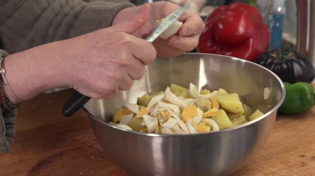 Woman's hands slicing boiled eggs for a potato salad