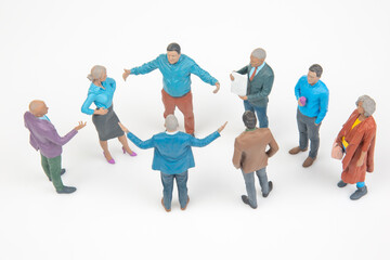 Obraz premium Miniature people gather for discussion in a circle on a white surface during a collaborative meeting at a neutral time