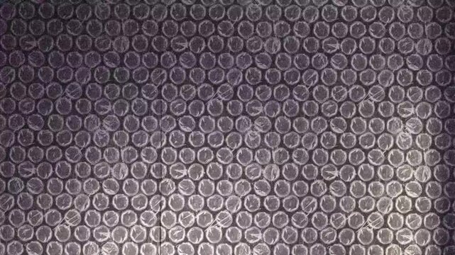 Geometric bubble wrap texture with stop-motion animation. Abstract monochrome plastic background with subtle blue and purple tints, film grain and dust. Widescreen 1080p horizontal loop.