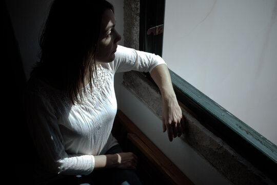 Portrait of a mid adult woman in casual clothing looking out of a window