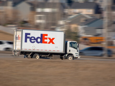 Calgary, Alberta, Canada. March 21, 2026. A FedEx delivery truck drives along a road with motion blur against a residential suburban background.